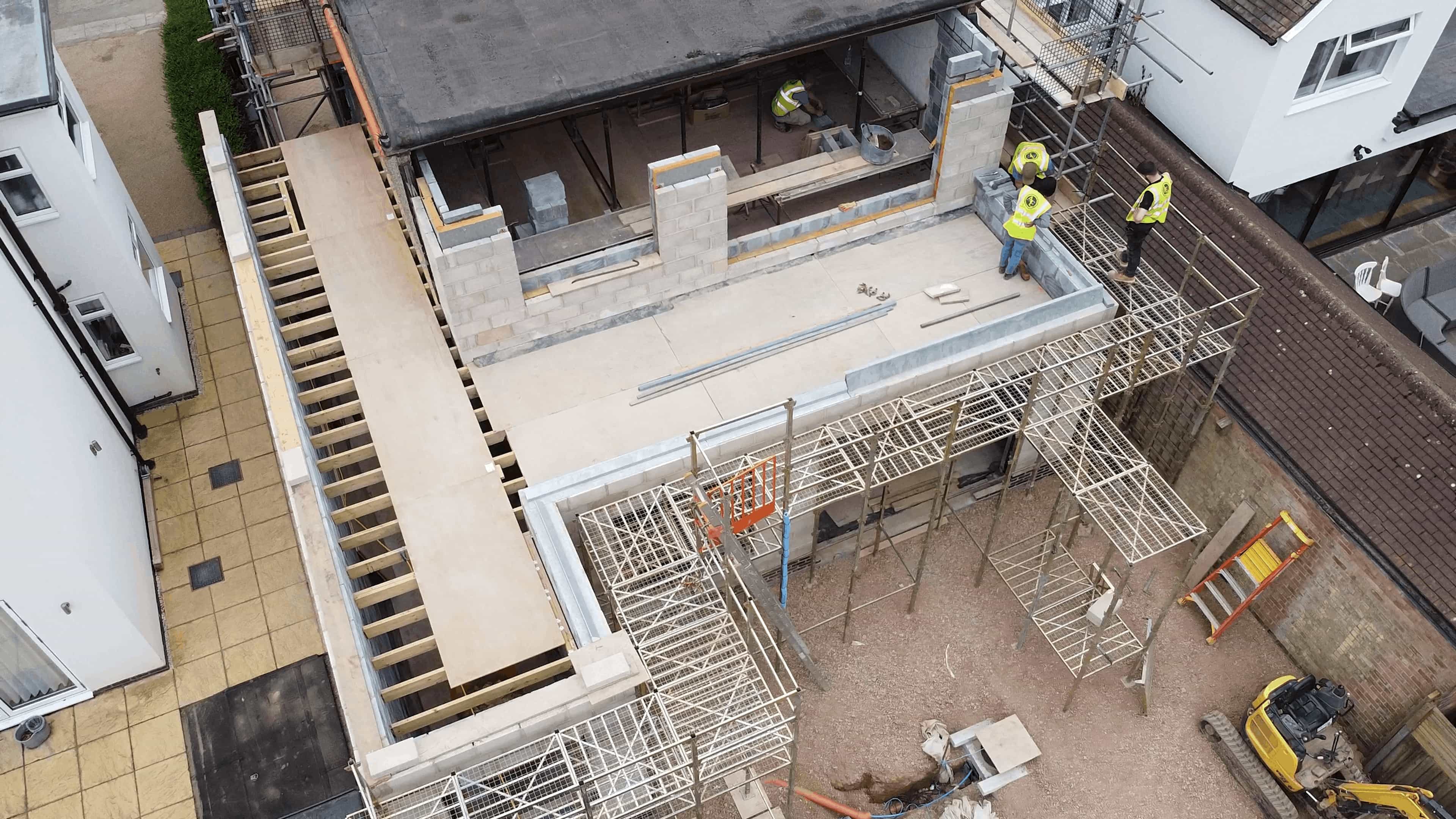 Aerial view of a residential construction site with workers on scaffolding