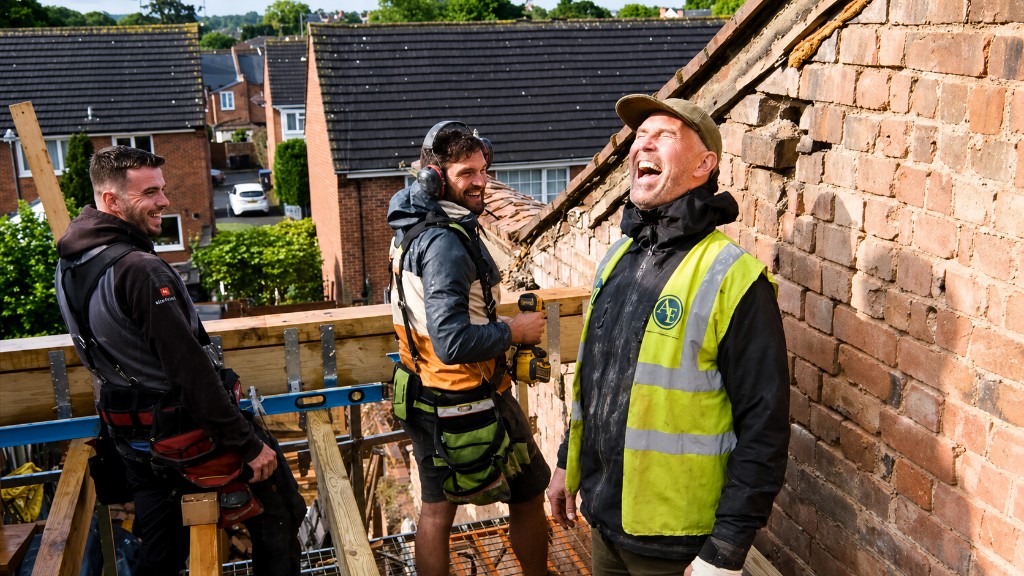 Three builders laughing together on a UK renovation site