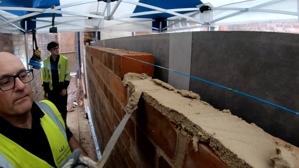 Bricklayers building a facing-brick wall to a string line