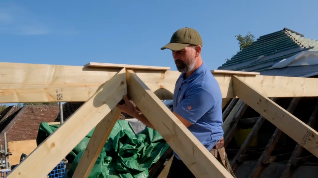 A carpenter fitting a timber roof frame