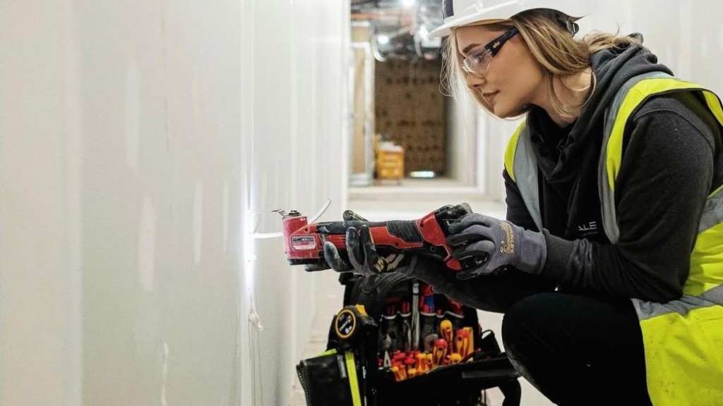 An electrician cutting a drywall opening with an oscillating tool