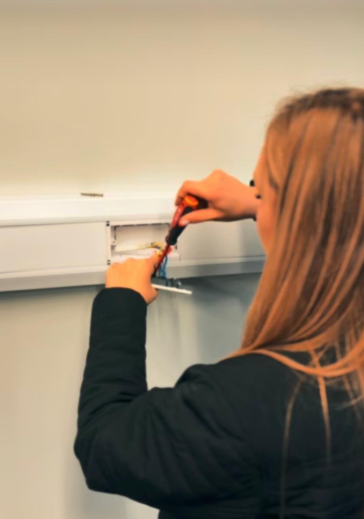 An electrician working on wiring in trunking
