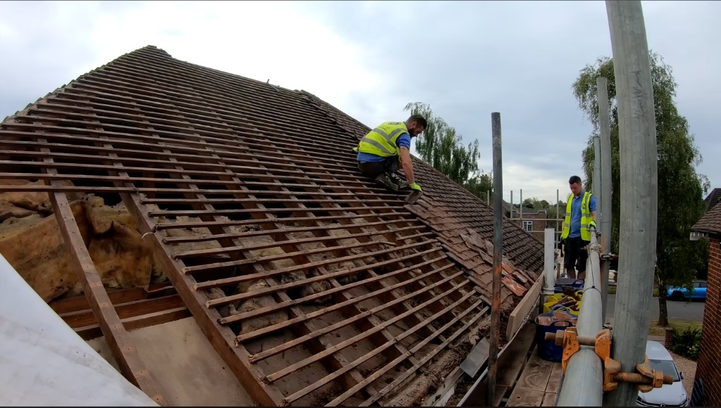 Roofers stripping a pitched roof from scaffold