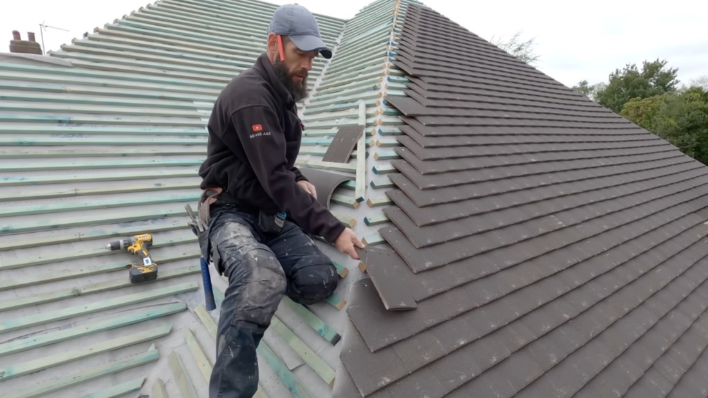 A roofer laying tiles on a pitched roof