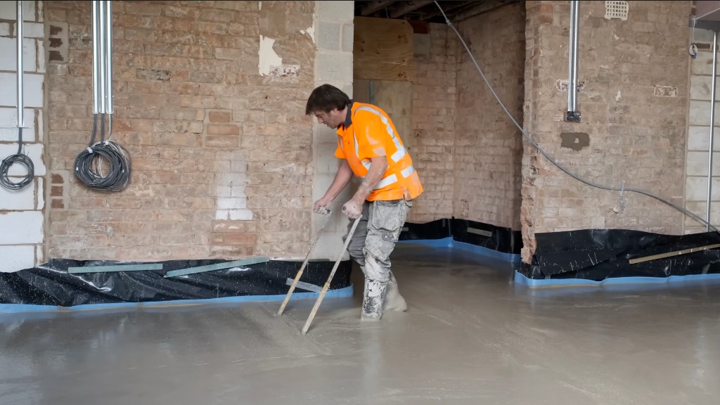 A floor layer leveling a wet screed
