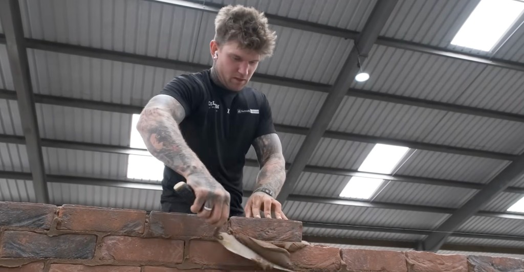 A bricklayer bedding a course of facing bricks